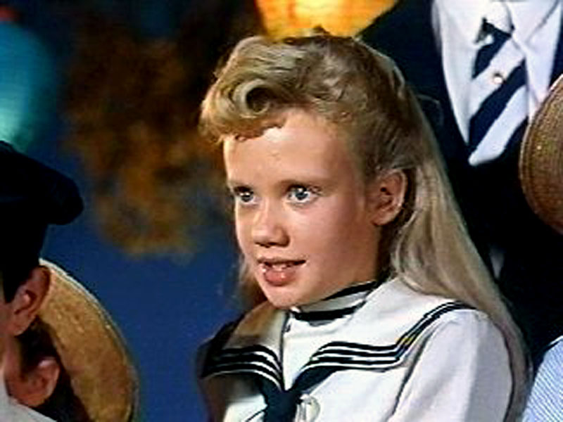 A white girl with blonde hair and blue eyes wearing a sailor suit